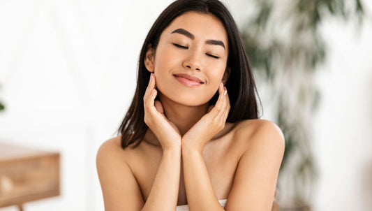 smooth chin dimples - young woman smiling and lightly holding her face with blurred spa background